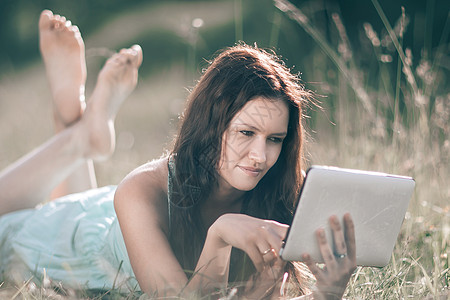 夏日躺在草坪上的数码平板电脑女孩药片女性教育技术阅读博主工作蓝图微笑成人图片