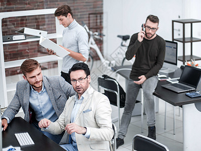 雇员坐在办公桌旁时在流动电话上说话会议职场工作日男人思维同事互联网经理团队就业图片
