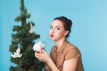 圣诞节 假期和人的概念  蓝色背景中装饰圣诞树的年轻风趣女人装潢幸福新年女士女性问候语享受头发金发女孩图片