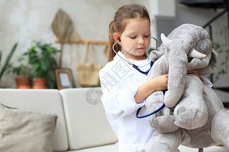 可爱的孩子打扮成医生 玩玩具大象 用听诊器检查它的呼吸情况童年诊断卫生职员病人婴儿护士女性女孩毛绒图片