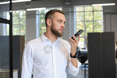 英俊的商务人士在办公室里使用语音识别应用程序男人记录企业家成人手机演讲商业麦克风人士男性图片