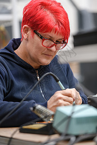 工厂生产设备的工业工人妇女焊接电缆技术员电气芯片工程红发电子产品桌子硬件职业半导体图片