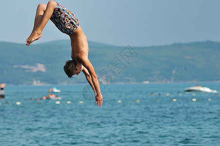 男孩跳海海岸闲暇海洋空气游泳者男人运动假期乐趣蓝色图片