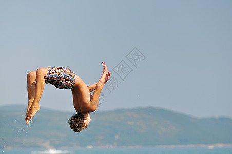 男孩跳海蓝色海滨闲暇潜水男性男人地平线天空假期游泳者图片