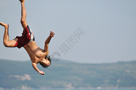 男孩跳海海岸身体喜悦游泳者蓝色青年潜水海洋假期海滨图片