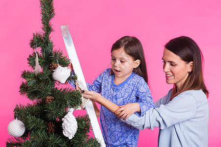 假期 家庭和圣诞节概念  母女在粉红色背景中装饰圣诞树庆典快乐女儿母亲工作室妈妈传统女士装潢闲暇图片