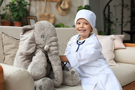 可爱的孩子打扮成医生 玩玩具大象 用听诊器检查它的呼吸情况童年儿科兽医衣服保健婴儿工作服工作病人卫生图片