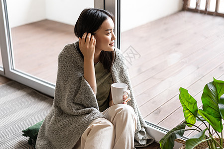 年轻浪漫的亚洲女人享受周末 清晨休息时喝茶 坐在窗户旁边的地板上看外观 这种想法是生活方式概念发烧流感卫生肺炎疾病疼痛互联网房子图片