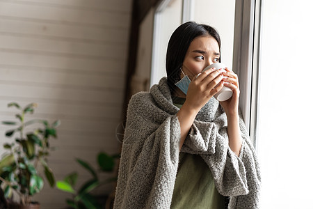 生病的亚洲女孩 喝着热茶 呆在家中隔离 看着窗外 感到不舒服和悲伤痛苦感染流感互联网窗户毯子鼻子杯子疼痛肺炎图片