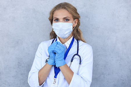 戴医疗面具的女医生 带着听诊器 看着在灰色背景上隔绝的照相机疾病医院推杆手套卫生护士安全工人职业女孩图片