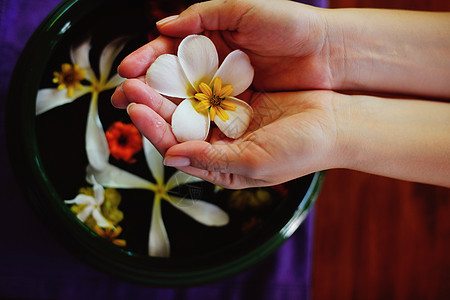 女性的手和水中的花芳香女士温泉花瓣药品美甲指甲手指沙龙皮肤图片