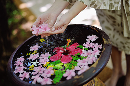 女性的手和水中的花花瓣指甲美甲手指皮肤女士护理女孩洗澡温泉图片