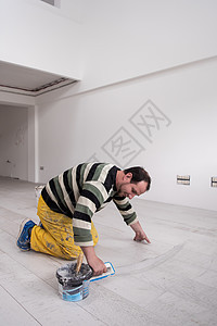 填满陶瓷木效应砖间间空间的提架工作接缝橡皮安装工人地板建造地面制品装修图片