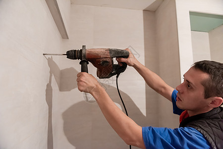 建筑工人在卫生间钻探洞孔职业木匠男人乐器工人服务工具噪音钻头房子图片