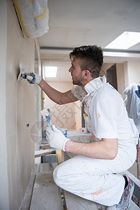 建筑工人在石膏墙上贴石膏工具工作建筑职业建设者木板材料墙壁房子男性图片