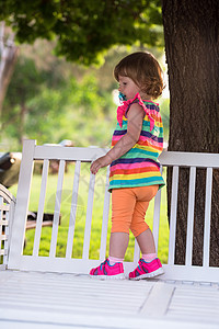 坐在木板凳上的可爱小女孩女性孩子公园女孩裙子快乐喜悦情感头发长椅图片