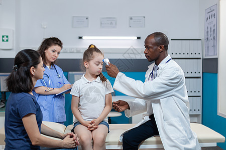 非洲裔美国儿科医生将医用红外线温度计放在小女孩额头上图片