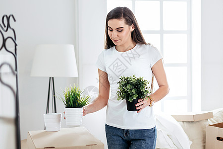年轻女人把她的东西放在新的公寓里搬迁牛仔裤财物抵押家庭包装植物生活喜悦窗户图片