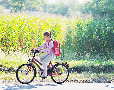 骑自行车上学的女中学生孩子乐趣童年旅行运动闲暇头盔女学生喜悦活动图片