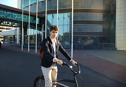自信的年轻商务人士在镇上街上骑着自行车走路商务商业骑术快乐套装工作男性职场建筑生态图片
