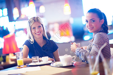 女孩在餐厅有咖啡喝女性闲暇朋友桌子杯子快乐微笑饮料女士果汁图片