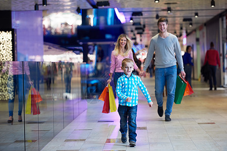 有购物袋的年轻家庭购物狂母亲购物者零售女孩微笑儿子成人女士父亲图片