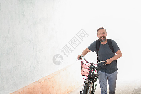 带背包的潮男推着一辆旧式自行车旅行男性城市冒险街道胡须活动潮人男人齿轮图片
