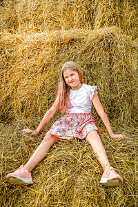 一个长头发的金发金发女孩 在炎热的夏日坐在稻草堆上图片