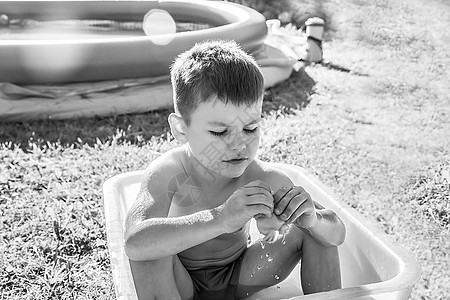 坐在浴缸里的悲伤的男孩子 坐着黑色和白色照片男人玩具黑与白小屋卫生儿子笑声情绪童年乐趣图片