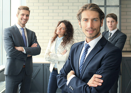 年轻的商务人士和他关于背景的学术会议一起在办公室里站着领导团队男性套装人士职员公司成功员工工作图片