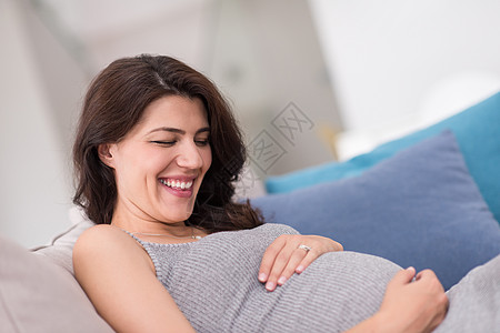 在家沙发上坐着的孕妇成人母亲闲暇公寓家庭婴儿房子母性身体怀孕图片
