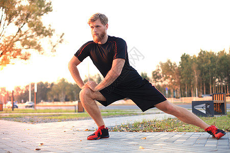 英俊的年轻男子在户外站着跑跑前做伸展运动重量福利城市男人男性身体成人活动肌肉锻炼图片