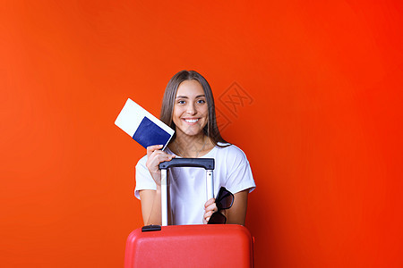 穿暑期散装的年轻旅游女孩 带着太阳镜 红色手提箱 在红色背景下被孤立的护照游客闲暇航程飞机树干旅游女士冒险行李手提包图片