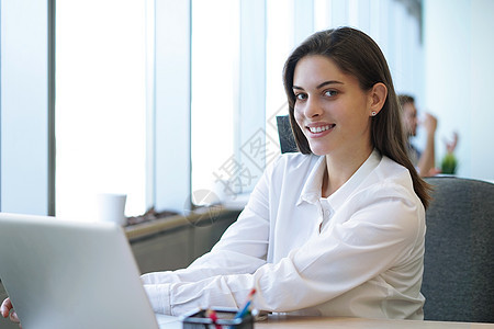 美丽的女商务人士在办公室工作时看着摄影机 微笑着笑容商务衣领职业成功女士会议讨论团体文档职场图片