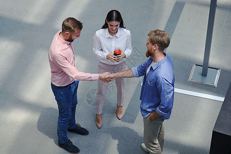 在创意办公室与同事站在一起握手的年轻现代人的顶视图专注风暴合作幸福问候语男人团队业务商务头脑图片