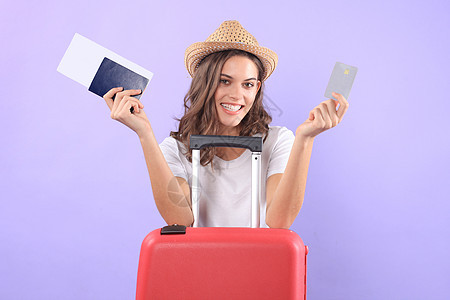 穿暑期临时服装的年轻旅游女孩 带太阳眼镜 红色手提箱 紫底护照和孤立的紫底护照冒险航程文档树干航空公司飞机场飞机假期行李旅行图片
