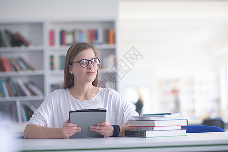 使用平板电脑在学校图书馆学习的女学生女孩微笑大学互联网青年教育女士图书馆眼镜成人图片