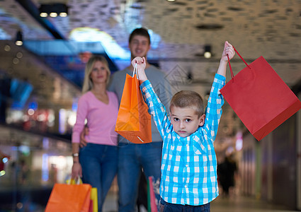 有购物袋的年轻家庭儿子微笑父母孩子零售购物中心男人店铺妈妈团体图片
