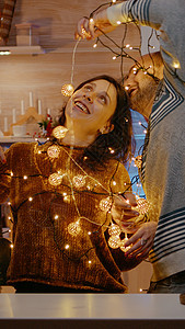 欢快的人被喜庆的灯光缠在一起桌子花环装潢季节假期新年已婚男人礼物家庭图片