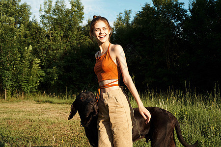 夏季在田里玩狗友情的女运动员日落友谊猎犬成人喜悦太阳海滩训练晴天动物图片