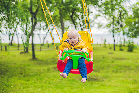快乐的小男孩骑在公园的摇摆幸福女性童年乐趣操场相机父亲微笑游戏孩子图片