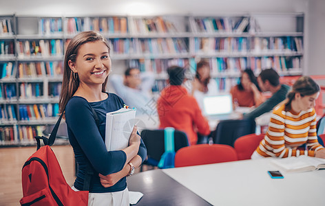 学生使用笔记本和学校图书馆学习书柜家庭作业知识文学图书管理员女孩教育小说图片