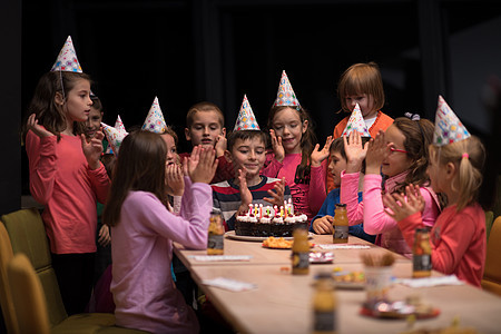 年轻男孩欢喜地庆祝他的生日孩子们礼物女孩们微笑房间男孩们蛋糕友谊朋友们喜悦图片