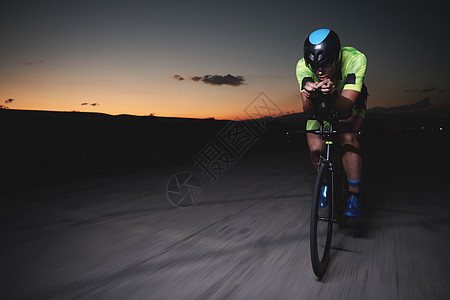 夜里快速骑自行车的三重运动员训练运动活力钢铁侠耐力赛车手头盔健康行动速度图片