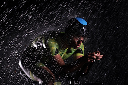 在雨夜快速骑着自行车的三亚马龙运动员运动赛车手速度竞赛头盔黑色行动钢铁侠男人活力图片