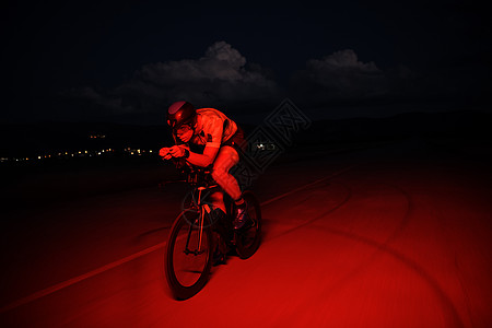 夜里快速骑自行车的三重运动员行动健康黑色钢铁侠男人速度头盔竞赛赛车手运动图片