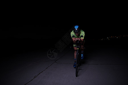 夜里快速骑自行车的三重运动员头盔行动速度运动铁人训练耐力健康钢铁侠竞赛图片