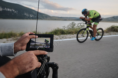 电影摄影师拍摄三亚特隆自行车运动员的动作视频驾驶速度相机行动训练钢铁侠头盔铁人运动图片