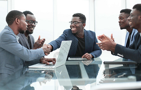 愉快的商业伙伴们在办公室开会时握手 握手电脑团队团体伙伴职员玻璃合同管理人员顾客协议图片