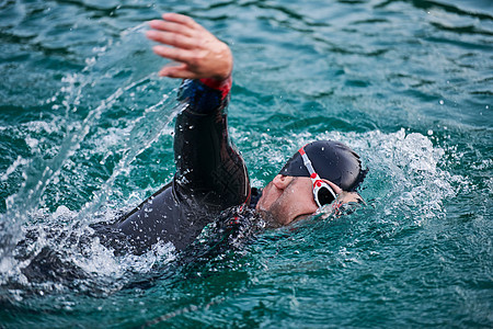 穿着湿衣服在日出湖上游泳的三亚体运动员游泳衣潜水耐力速度钢铁侠竞赛运动装力量锻炼活力背景图片